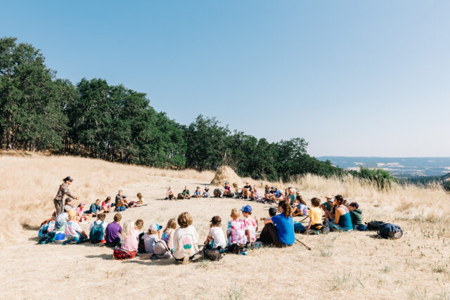 A big group of kids in a circle on a high hill